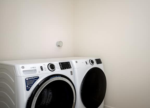 A white front loading washing machine with a black door is in a room.
