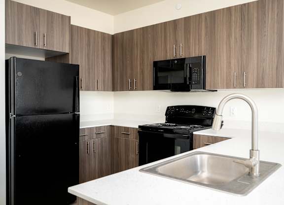 A kitchen with a black fridge, black microwave, and black stove.