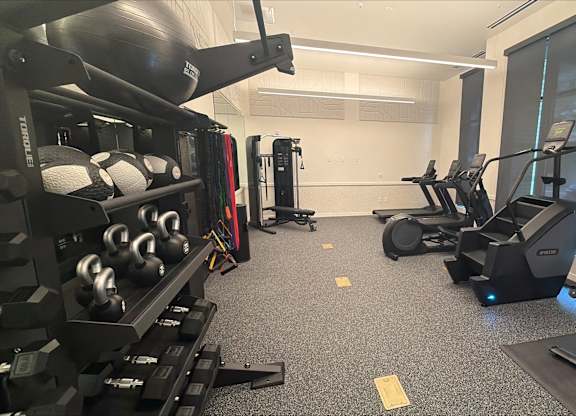 A gym with a variety of equipment including weights and treadmills.