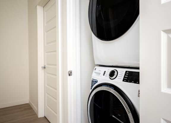 A white washing machine is placed in a corner of a room.
