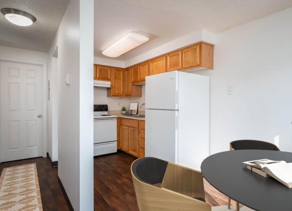 a kitchen with white appliances and wooden cabinets and a dining room table