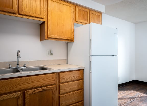 an empty kitchen with a white refrigerator and wooden cabinets