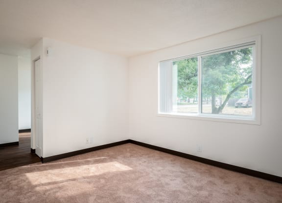 an empty room with a large window and carpet