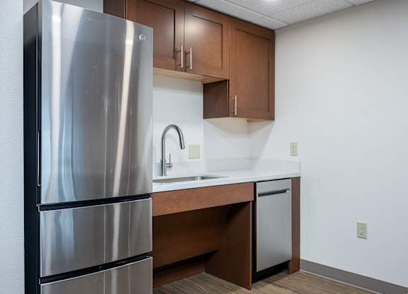 A kitchen with a stainless steel refrigerator and wooden cabinets.
