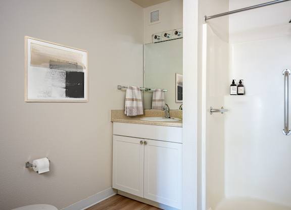 A white bathroom with a toilet, sink, and shower.