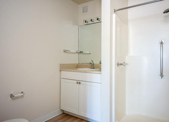 A white bathroom with a sink and a shower.