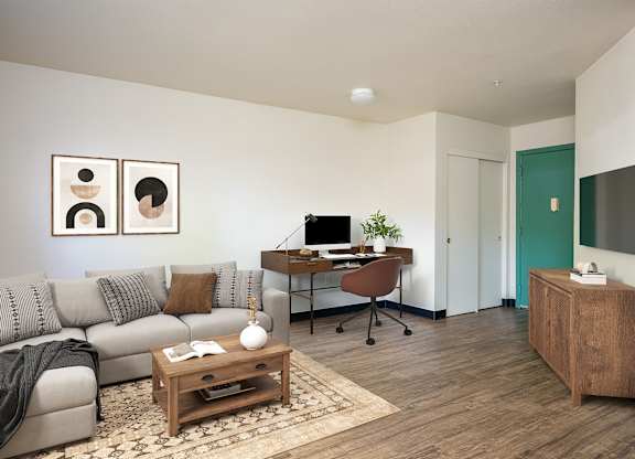 A living room with a grey couch, a wooden coffee table, and a TV on the wall.