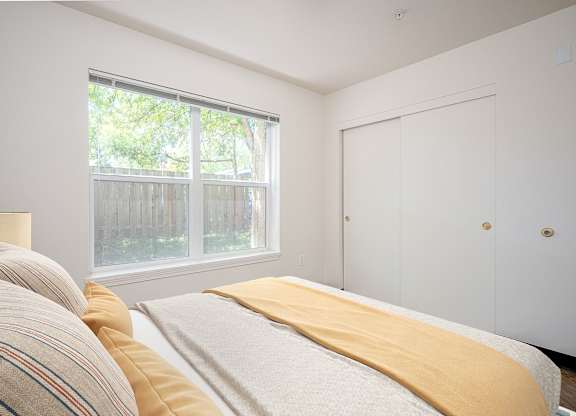 A bedroom with a bed, a window, and a door.