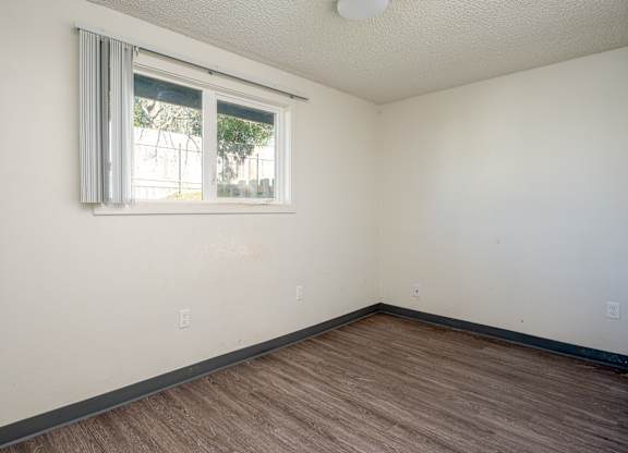 A room with a window and wooden flooring.