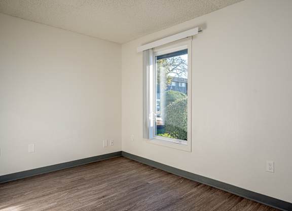 A room with a window and wooden flooring.