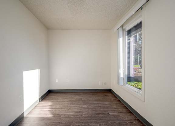 A room with a window and wooden floor.