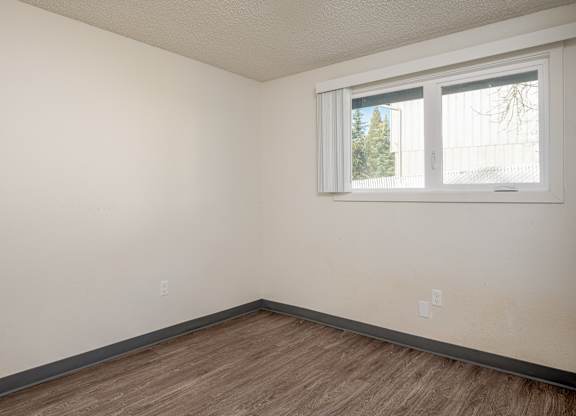 Empty room with a window and wooden floor.