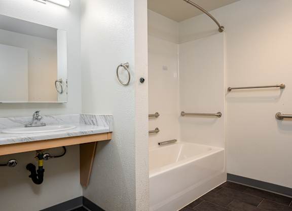 A white bathroom with a sink, mirror, and bathtub.