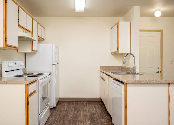 A kitchen with white appliances and wooden cabinets.