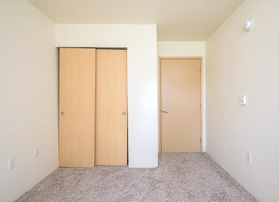 Two doors are closed in a room with carpeted floor.
