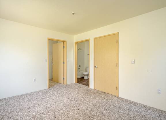A room with a carpeted floor and three doors.