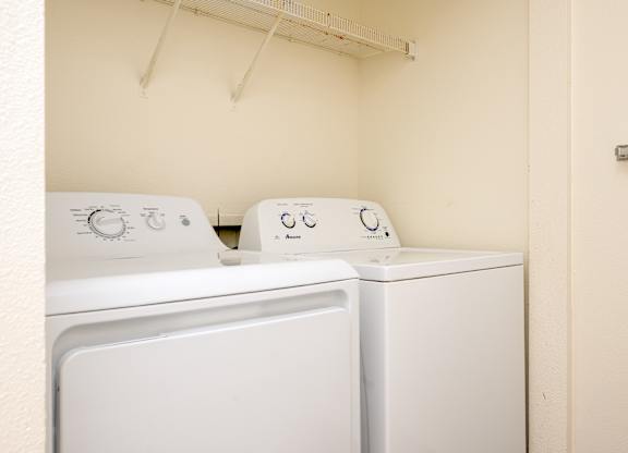 Two white front loading washing machines in a small laundry room.