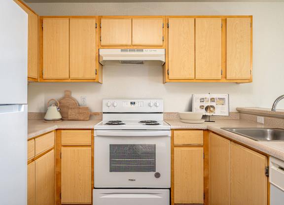 A kitchen with wooden cabinets and a white stove top oven.