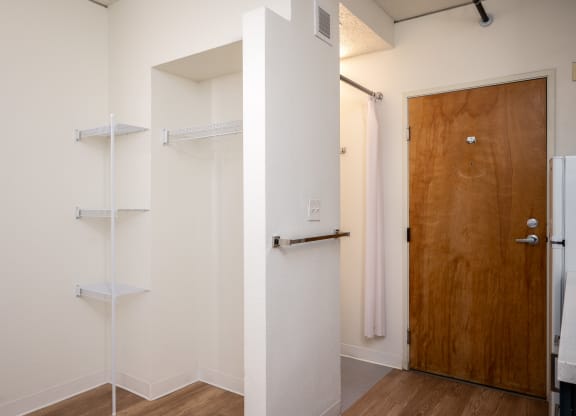 a walk in closet in a bedroom with a wooden door and white walls