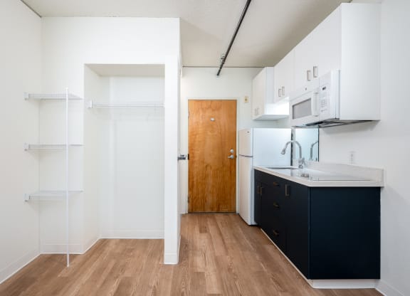 a kitchen with white walls and a wooden floor