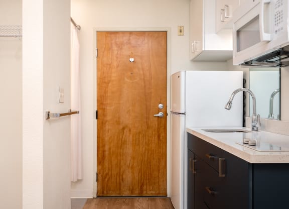 a kitchen in a small apartment with a wooden door and white appliances