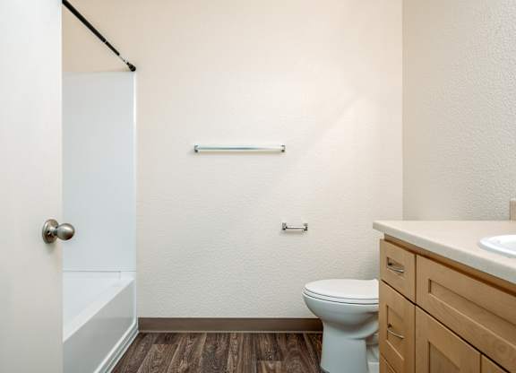 A white toilet sits in a bathroom with a white door and a white sink.