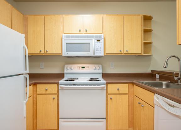 A kitchen with a white stove and wooden cabinets.