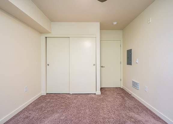 A room with a carpeted floor and two white doors.