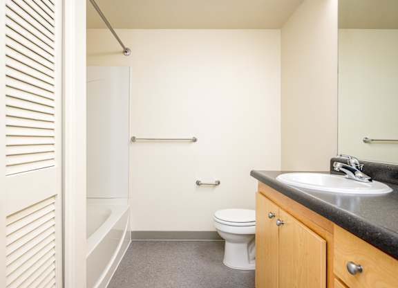 A bathroom with a toilet, sink, and a shower with a glass door.