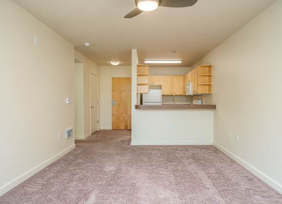 A room with a kitchenette and a fan.