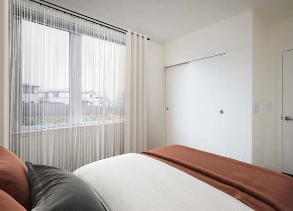 A bedroom with a large bed and a view of the city through the window.