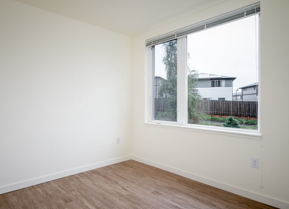 an empty room with a large window and wooden floors