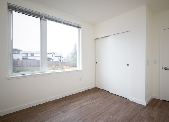 an empty bedroom with a large window and a door
