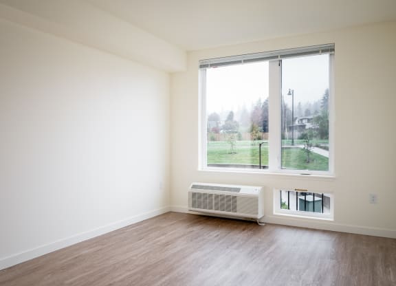 an empty room with a large window and wood floors