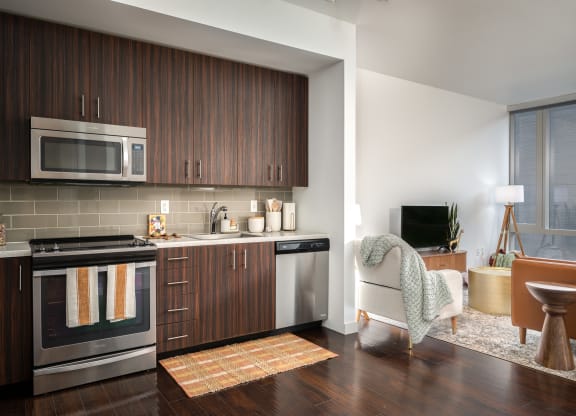 a kitchen and living room with wooden cabinets and stainless steel appliances