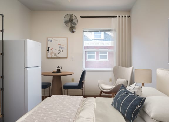 a bedroom with a bed and a refrigerator and a table with chairs