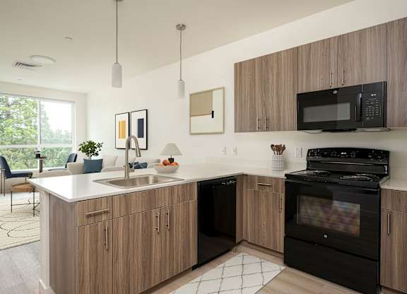 A modern kitchen with wooden cabinets and black appliances.