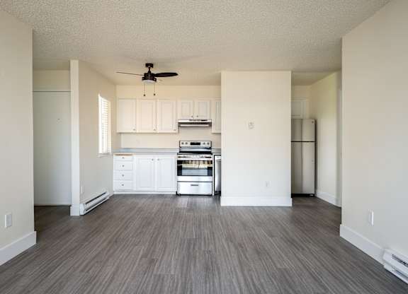 A spacious kitchen with white cabinets and a wood floor.