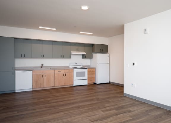 an empty kitchen with white appliances and wood floors