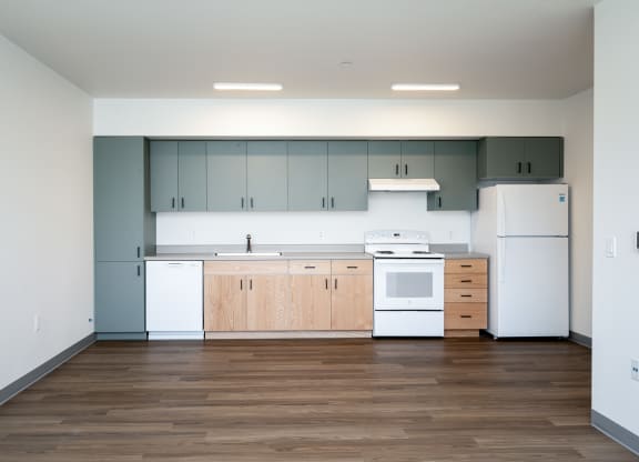 an empty kitchen with white appliances and wood floors