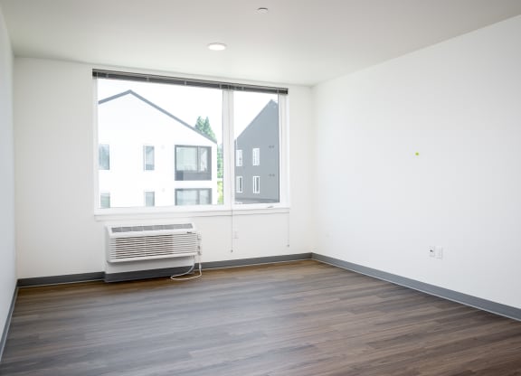 an empty living room with a large window and wooden floors