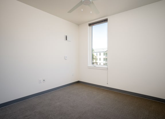 an empty room with a window and a ceiling fan