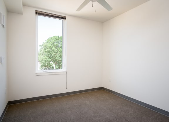an empty room with a window and a ceiling fan
