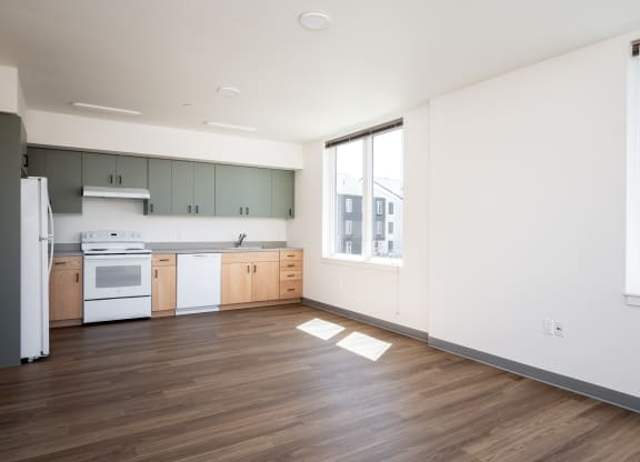 an empty kitchen with white appliances and wood flooring