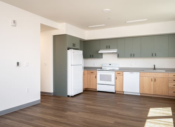 an empty kitchen with white appliances and wood floors