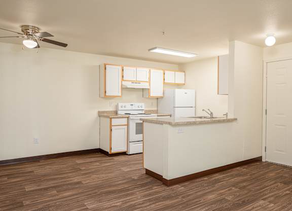 A kitchen with white cabinets and a wooden floor.