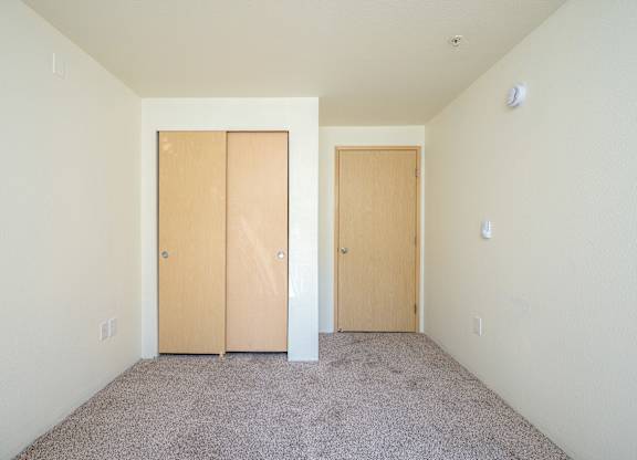 A room with two doors and carpeted floor.