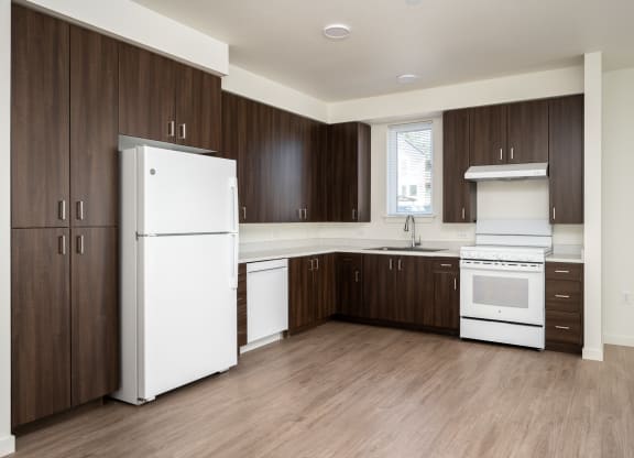 an empty kitchen with white appliances and wooden cabinets