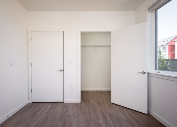 a bedroom with white walls and a window and a closet