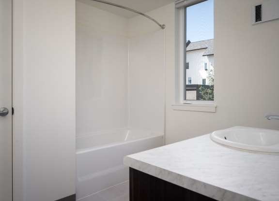 a bathroom with a sink and a shower and a window